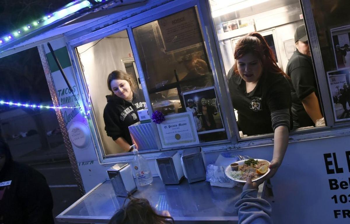 Alejandra Gonzalez, left, and Bianca Loza, right, of El Premio Mayor serve free tacos to the homeless outside Poverello House in this Fresno Bee file photo from 2017.