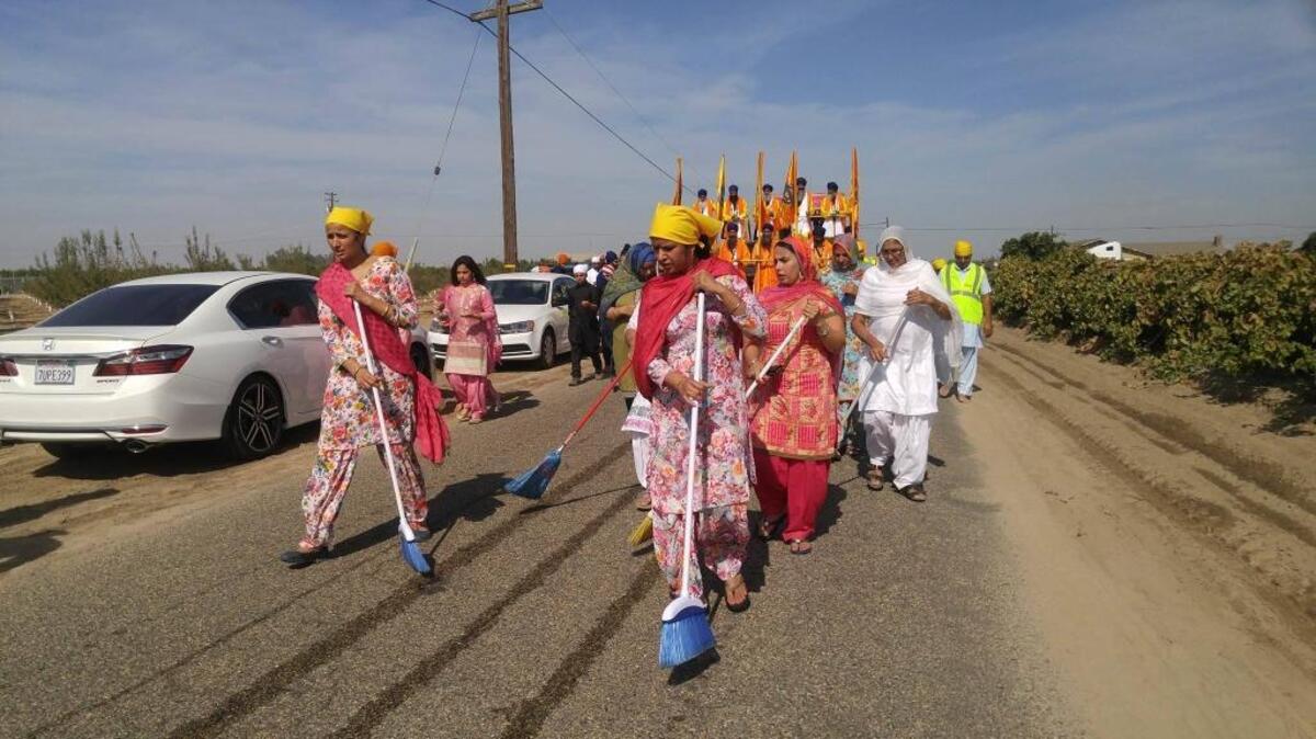Women sweep ahead of the leading float and shrine during the Sikh parade in Fowler Sunday, Oct. 23, 2016.