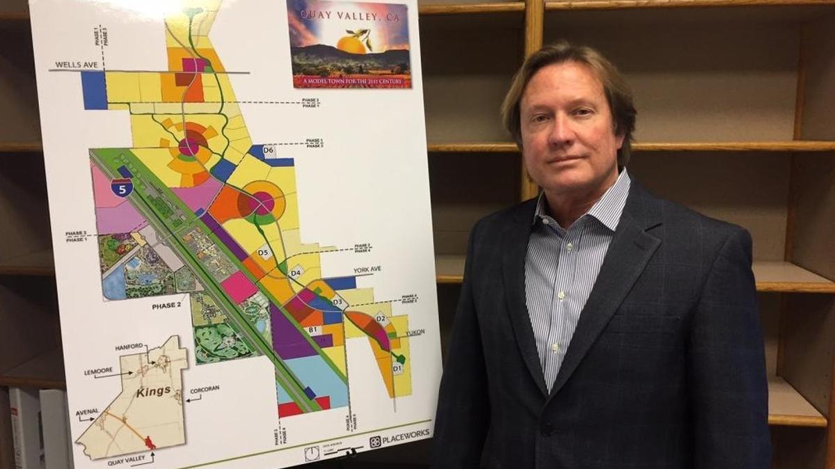 Quay Hays stands before a map last year showing the proposed Quay Valley development in Kings County.