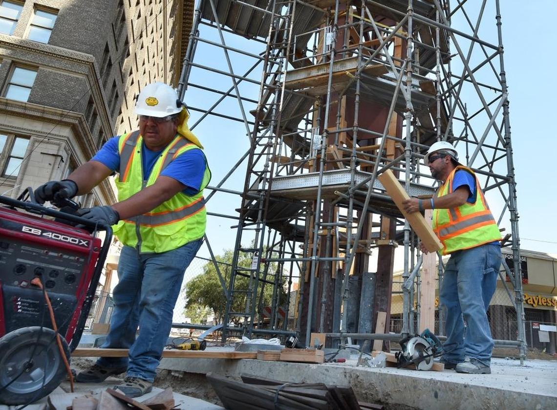 Jose Andasol, left, and Carlos Flores, both of Sculpture Conservation Studio, work on the protective covering of the historic 60-foot-tall Fulton Mall clock tower Wednesday morning in preparation for its move about 60 feet away from the Mariposa and Fulton intersection next Tuesday by crane.