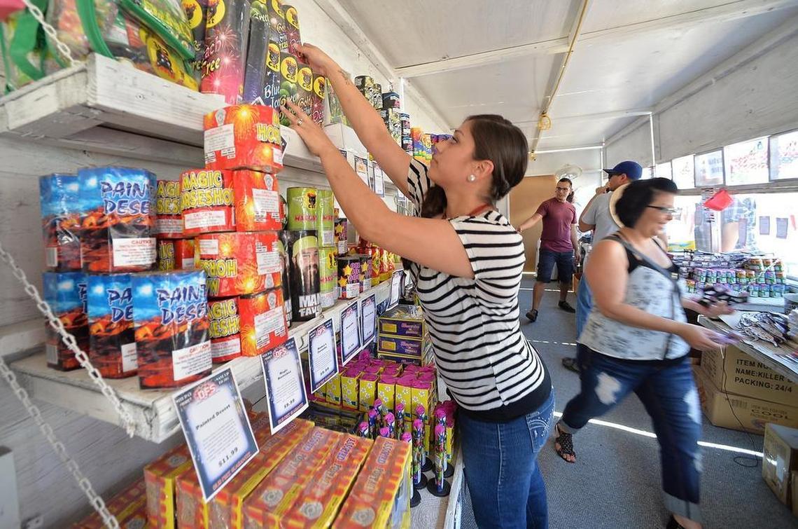 Crystal Aldape, 26, of Fresno, reaches for boxes of fireworks as customers line up to buy remaining supplies at a deep discount at a fireworks stand near Blackstone and Shaw avenues in Fresno, California, on July 5, 2015.
