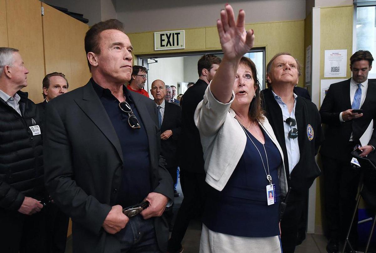 Buchanan High learning director Debi Kelly, right, describes the energy-efficient design of a school room to former Governor Arnold Schwarzenegger, left, with former Govenor Jerry Brown in the far center background Thursday, Dec 12, 2019 in Clovis. The event celebrated reaching the goal for Schwarzenegger’s 2006 Million Solar Roofs Initiative.
