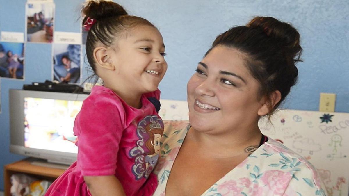 Salina Rios, 19, a participant in Teen Success Inc., a program that helps teen mothers in the central San Joaquin Valley, holds her daughter Nataliee Villagrana, 2, during an open house for the program at Fresno Barrios Unidos last September.