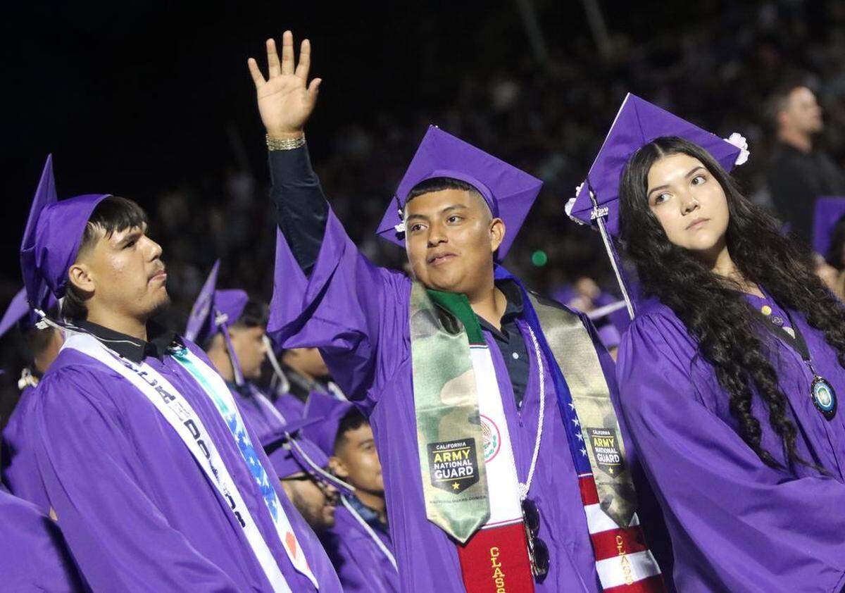 Madera South High graduate Rigoberto Eugenio Rodríguez waves to the crowd during the graduation ceremony at Madera Memorial Stadium on June 7, 2023.