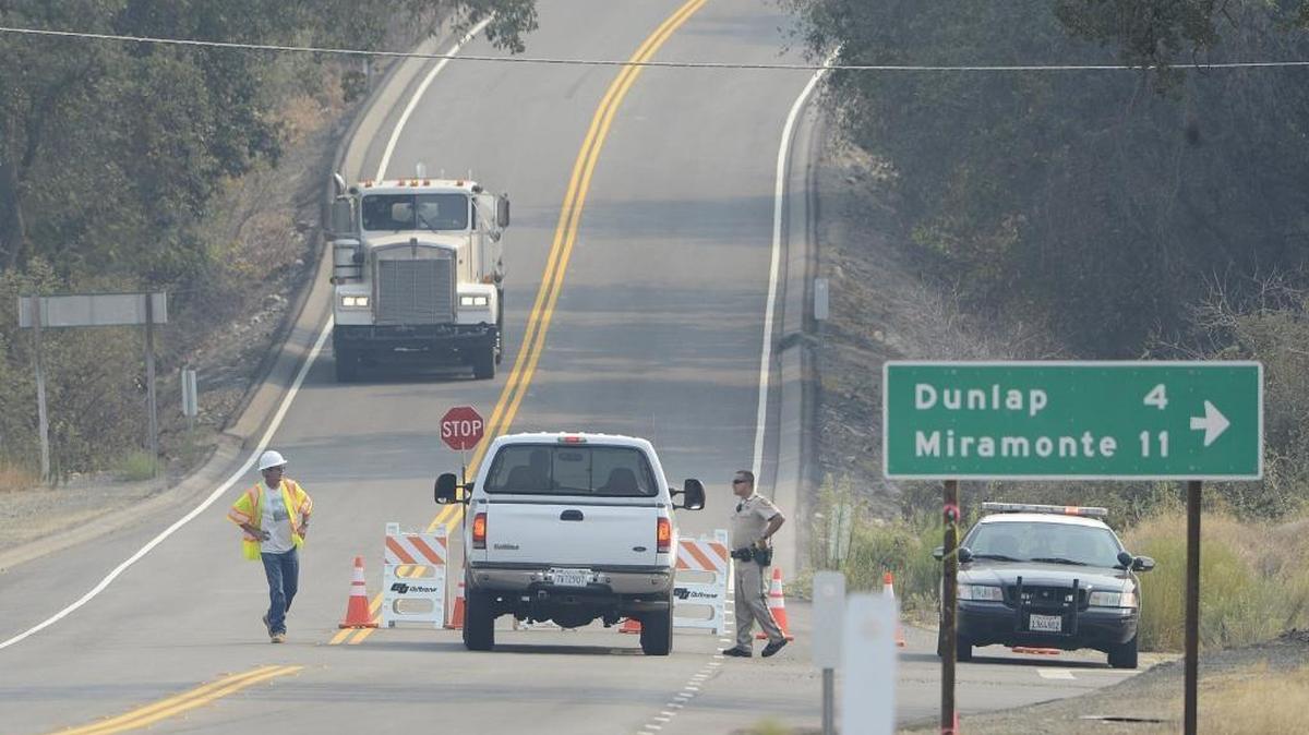
A California Highway Patrol officer directs vehicles around a road block on Highway 180 at Dunlap Road, which was closed to eastbound traffic because of the Rough fire Thursday. The Fresno County Sheriff’s Office Tuesday lifted evacuation orders for some – but not all – areas affected by the Rough fire.
