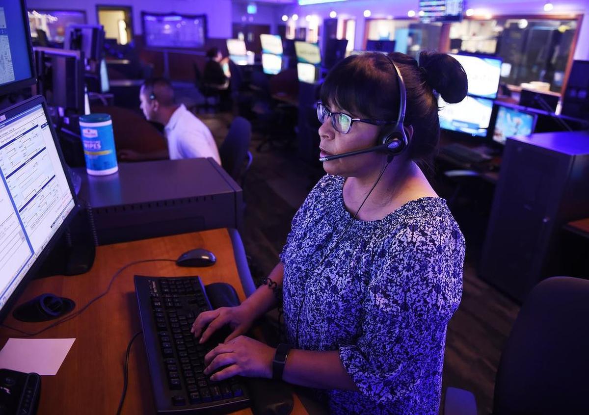 Cast in a blue light of an otherwise darkened room, Lydia Valdez, an ESD II, handles a call at the Fresno Police Department’s Dispatch Center Monday, July 30, 2018 in Fresno.