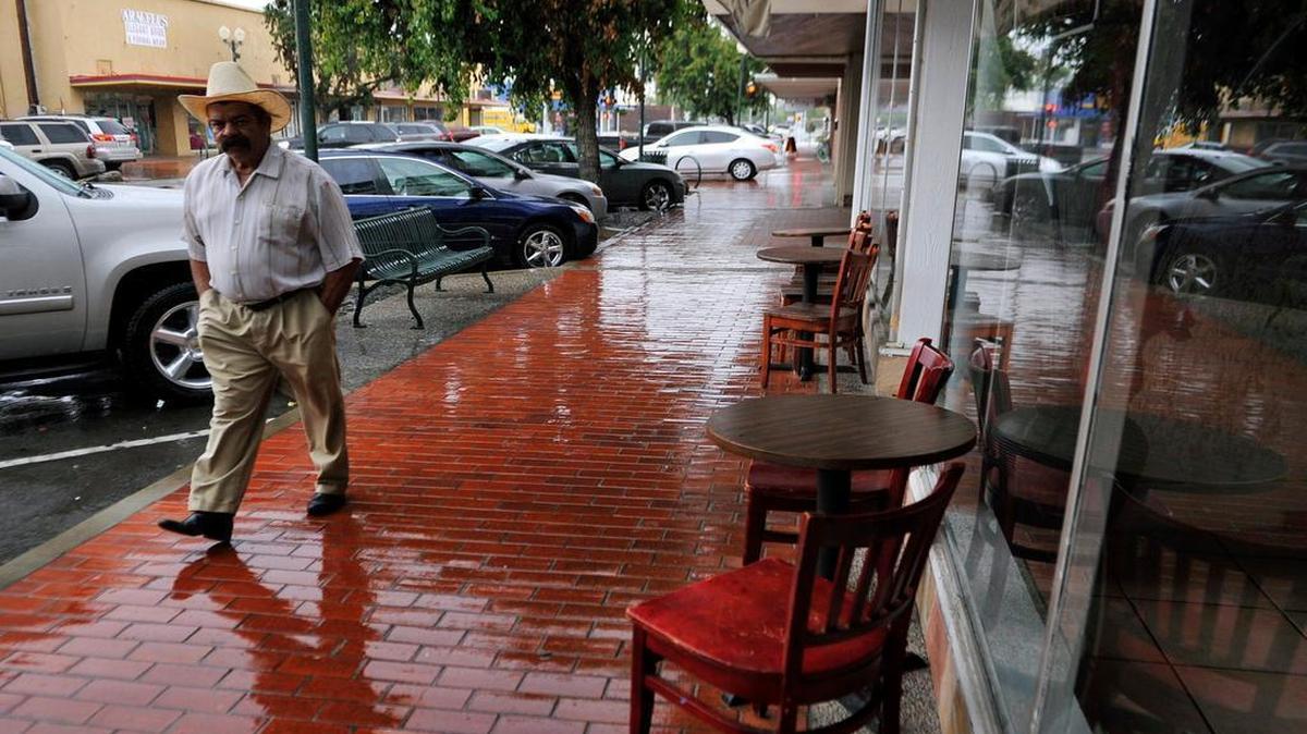 
Alfredo Ochoa walks past Fermin's Steak House as rain falls in downtown Sanger on July 9, 2015.
