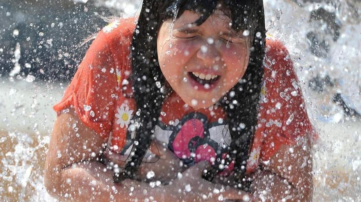 Angelica Perez, 8, gets a cool dousing under a water bucket feature at Dickey Playground during the hot Tuesday afternoon.
