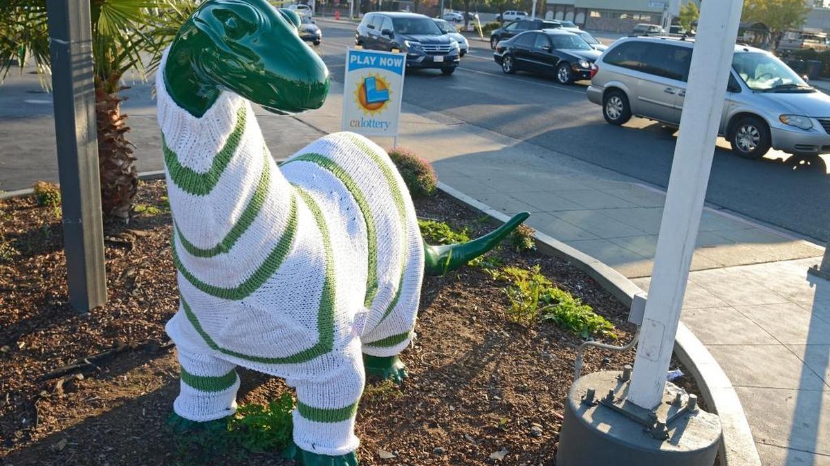 The dinosaur statue outside the Sinclair gas station at Bullard and Palm avenues in northwest Fresno sports a knitted sweater Wednesday, Nov. 11, 2015.