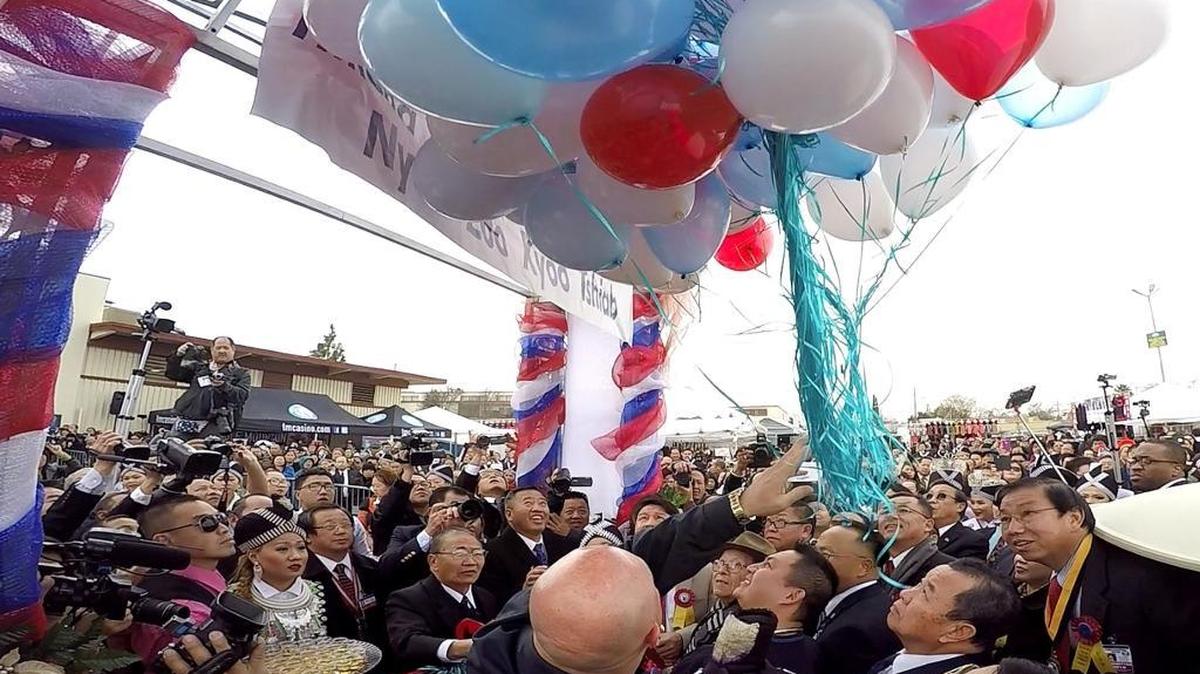 Fresno Police Chief Jerry Dyer, bottom center, helps release a cluster of red, white and blue balloons to formally kick off the Hmong International New Year celebration Saturday morning, Dec. 26, 2015 at the Fresno fairgrounds.