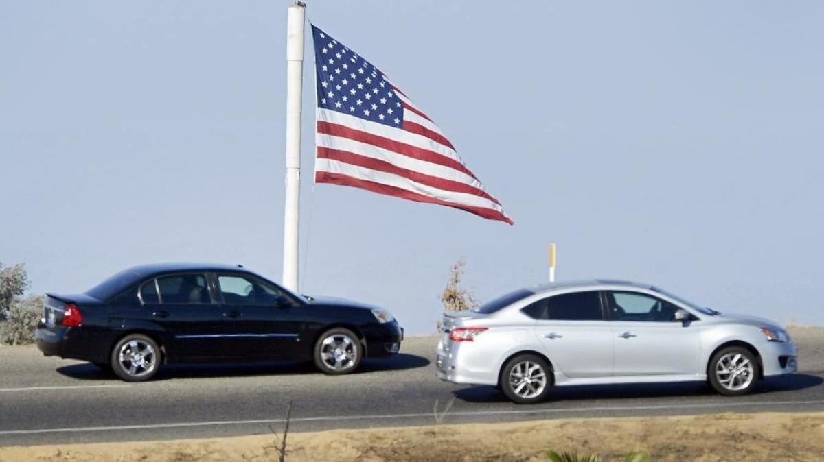 
Cars enter Highway 168 at Shaw Avenue on Thursday as the flag flies above Hedrick’s Chevrolet in Clovis.. The Clovis Planning Commission has opposed a proposal that could remove the large flag.  Hundreds of Clovis residents have voiced objections to the proposal.
