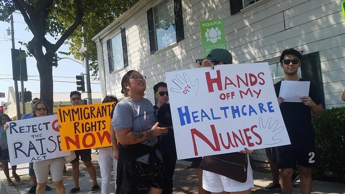Protestors in front of Rep. Devin Nunes’ office hold signs demanding he reject the RAISE Act and support the Affordable Care Act.