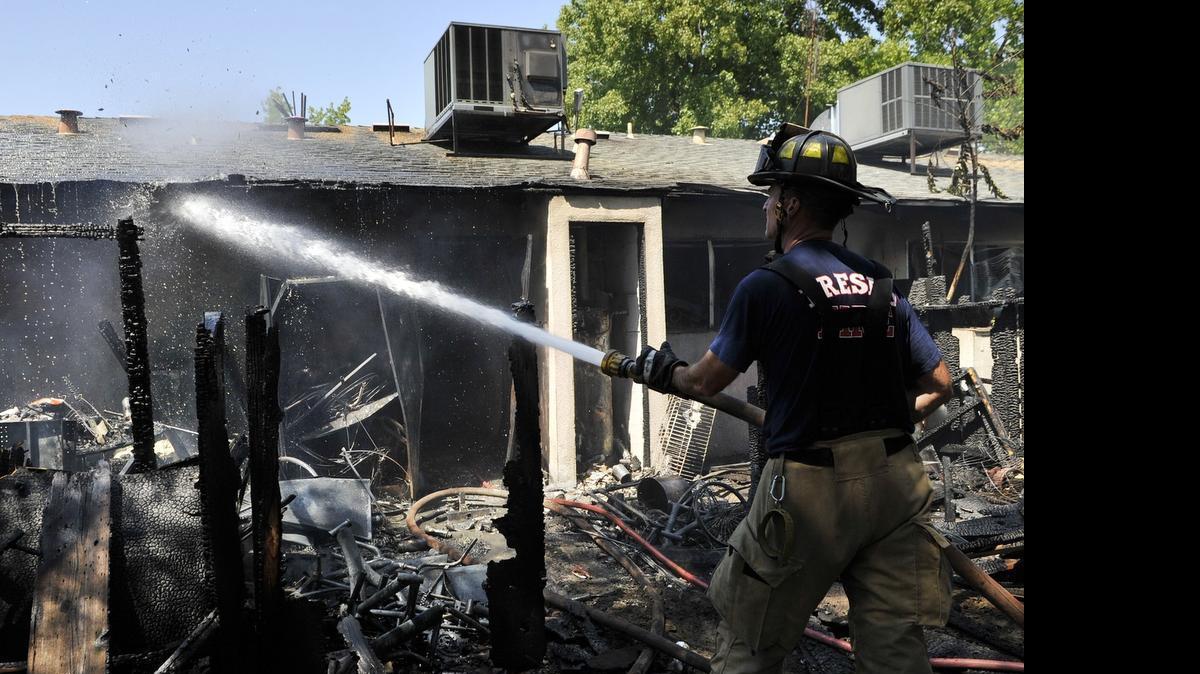 
Fresno Fire Department Station 6 firefighter Scott Griffith hoses down the rear patio following a two-alarm fire at the Villa Madrid Apartments along Ashlan Avenue east of First Street Wednesday afternoon, July 22, 2015 in Fresno, Calif.
