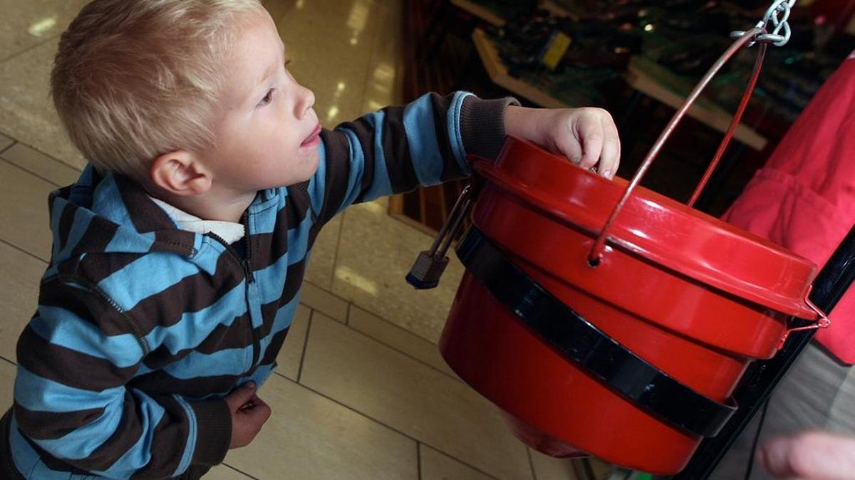 Jacob Evans reaches to try and drop coins into The Salvation Army donation bucket at Fashion Fair Mall in this file photo.