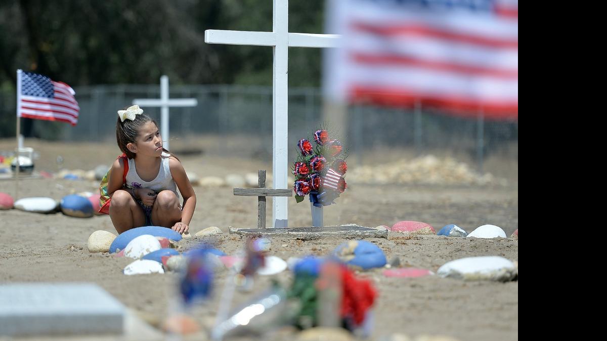 
Hailey Jeff, 7, of Clovis, sits next to a cross at her grandfather Henry Lee Jeff Jr.’s gravesite after the 20th annual Choinumni Memorial Day Gathering at the Choinumni Sacred Burial Grounds near Pine Flat Dam on May 24, 2015. The gathering honored and remembered Native American Veterans who served in the U.S. armed services.
