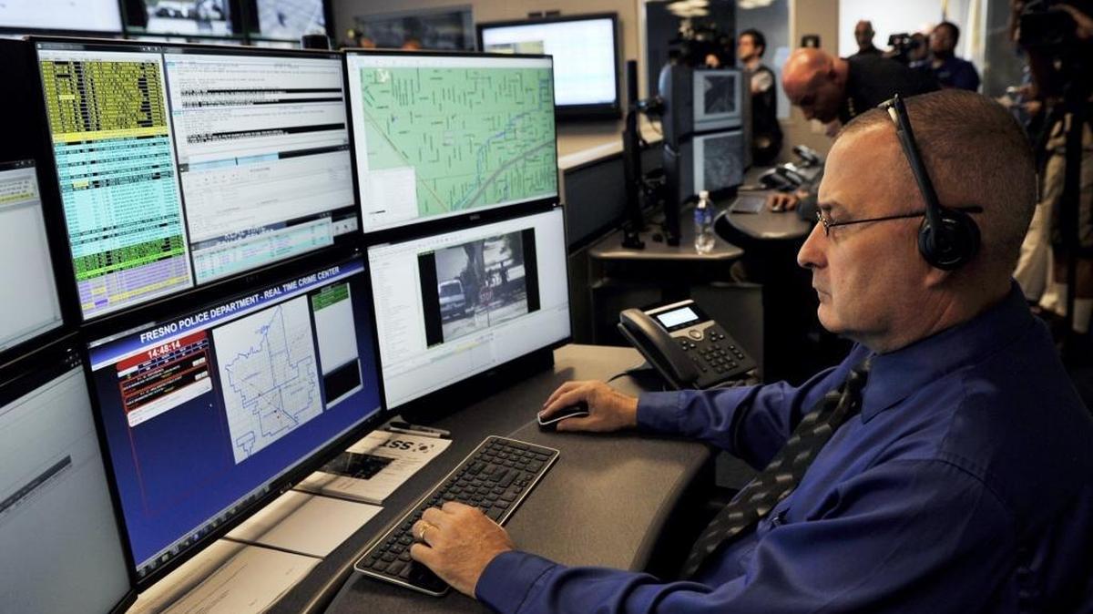 Fresno police officer Mike Toepfer, bottom right, sits monitoring one of many screens in the department's new Real Time Crime Center, a privately-funded computer hub located in police headquarters. The department hopes to add social media monitoring as part of the center.