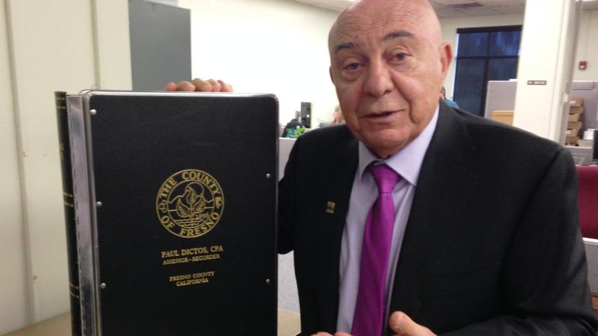 Fresno County Assessor-Recorder Paul Dictos holds a bound volume of recorded documents, one of about 20,000 books of property records and other types of documents that are held by his office dating to the county’s origins in the 1850s.