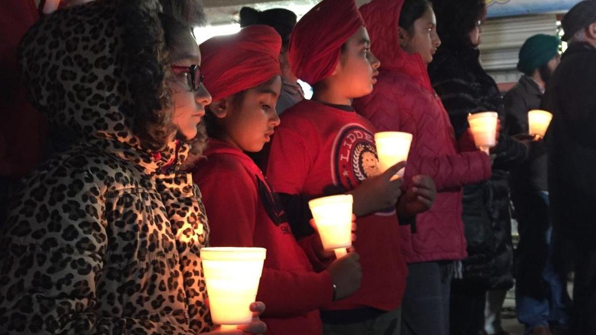 (Left to right) Keerat Brar, 6, Gursant Brar, 5, Anmol Brar, 8, and Simrat Brar, 9, watch a speaker talk during a candlelight vigil in front of The Shields Express Mart in central Fresno on Friday to remember a 68-year-old liquor store employee killed during an armed robbery on New Year’s Day.