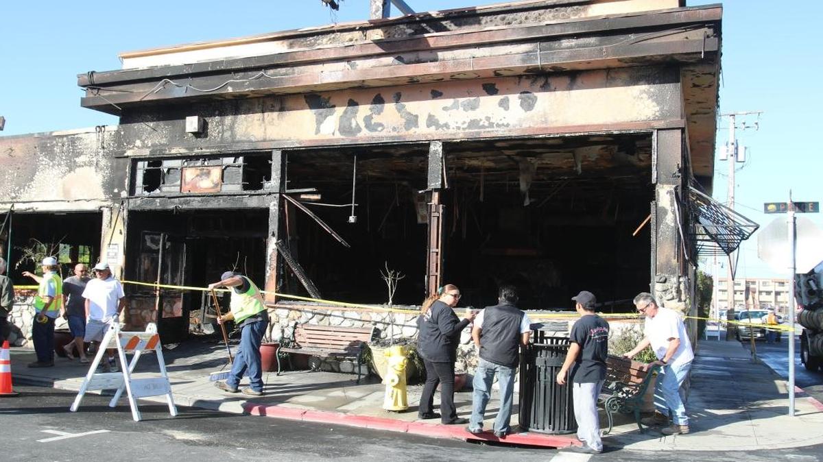Giuseppe’s Cucina Italiana restaurant in Pismo Beach was consumed by fire starting around 2 a.m. Saturday. Employees watch as crews clean up the sidewalks surrounding the building.
