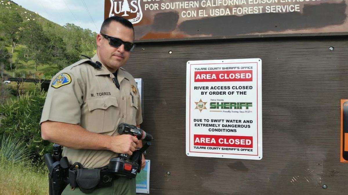 Tulare County Sheriff’s Deputy Mike Torres erects a sign at The Stairs access point stating that the Tule River is closed.