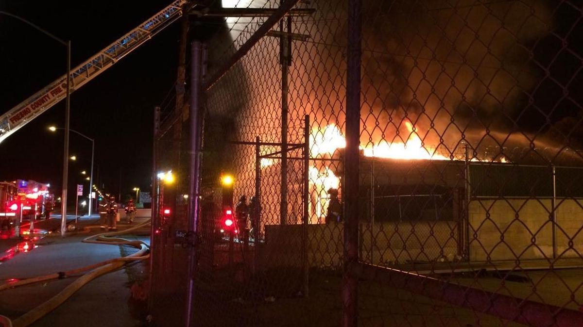Firefighters pour water from a ladder truck onto a commercial building Friday night, Dec. 4, 2015 in southwest Fresno.