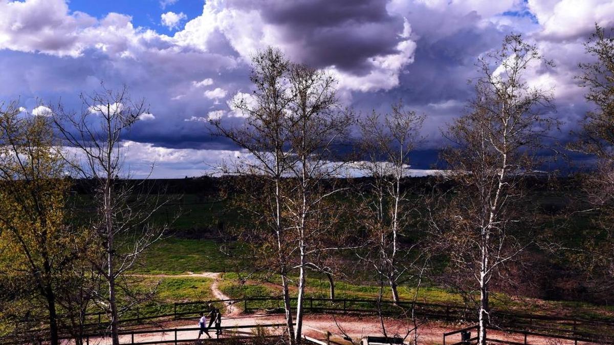 Walkers using the Eaton Trail near Woodward Park are framed by storm clouds on a March afternoon.