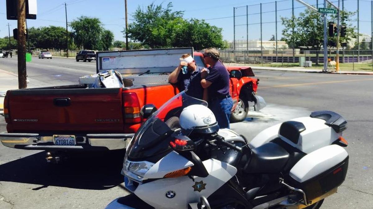 A man injured in a collision Friday in central Fresno is aided by a friend.