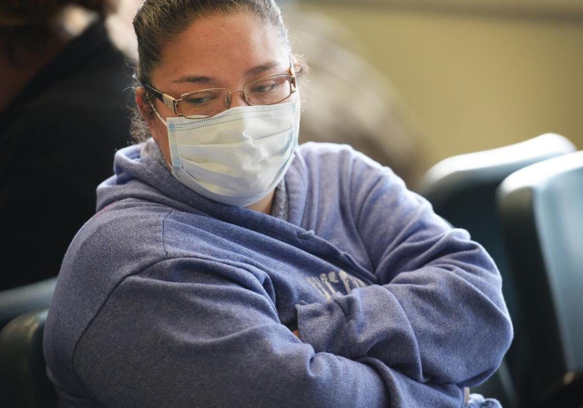 Claudia Cantu of Fresno, with flu symptoms, wears a surgical mask while waiting to see a doctor in the emergency department at Community Regional Medical Center in Fresno on Monday, Jan. 22, 2018.