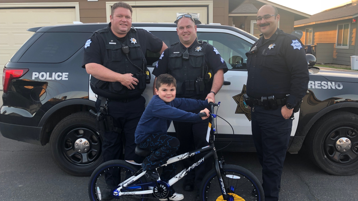Fresno Police Department officers pose with a 7-year old boy and his new bicycle. The officers pitched in to buy the boy a new bike after his bike was stolen.