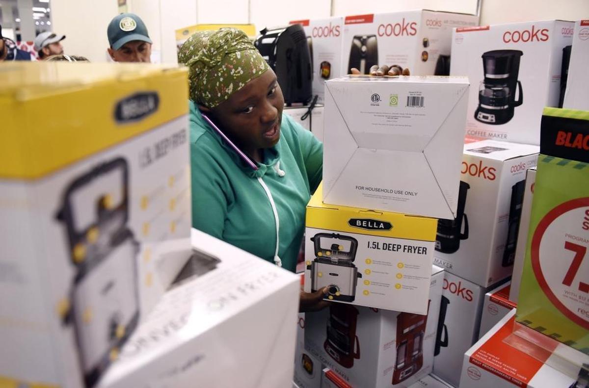 A woman talks on the phone as she grabs small appliances priced for Black Friday sales at JCPenney on Thursday afternoon, Nov. 23, 2017.