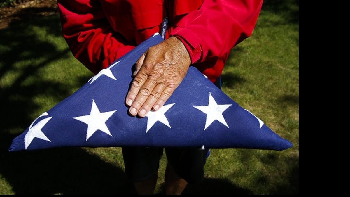 
Tim Haley holds an American flag folded in the traditional triangular shape, with only the blue union showing.
