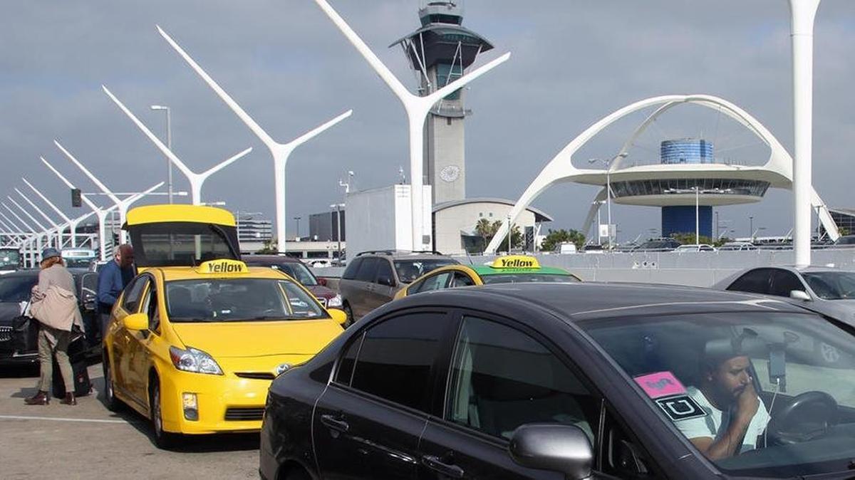 A driver with Uber and Lyft rideshare service stickers in the windshield jockeys for position with taxicabs and other vehicles at Los Angeles International Airport. Fresno Yosemite International Airport is developing a permit process to allow rideshare services to pick up and drop off passengers at the Fresno airport.