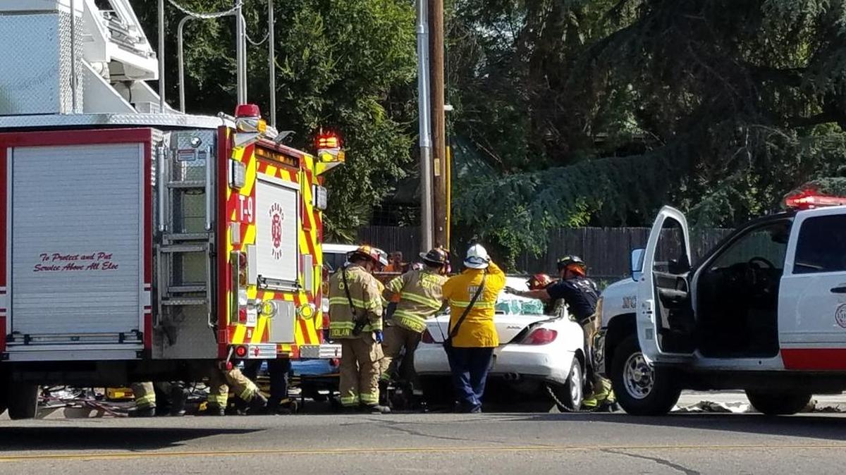 Fresno firefighters extract a woman from her car after she crashed into a power pole near the Fresno Chaffee Zoo on Monday, July 24, 2017.
