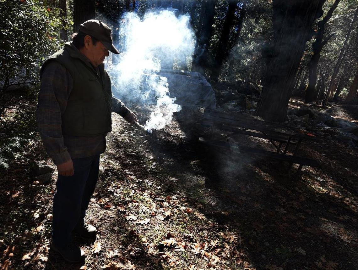 Past tribal chairman Tony Brochini burns sage to bless the ground where he once lived in a house. It was burned down in the 1960s, at the site of an ancestral Native American village, which is now being reconstructed in Yosemite Valley.