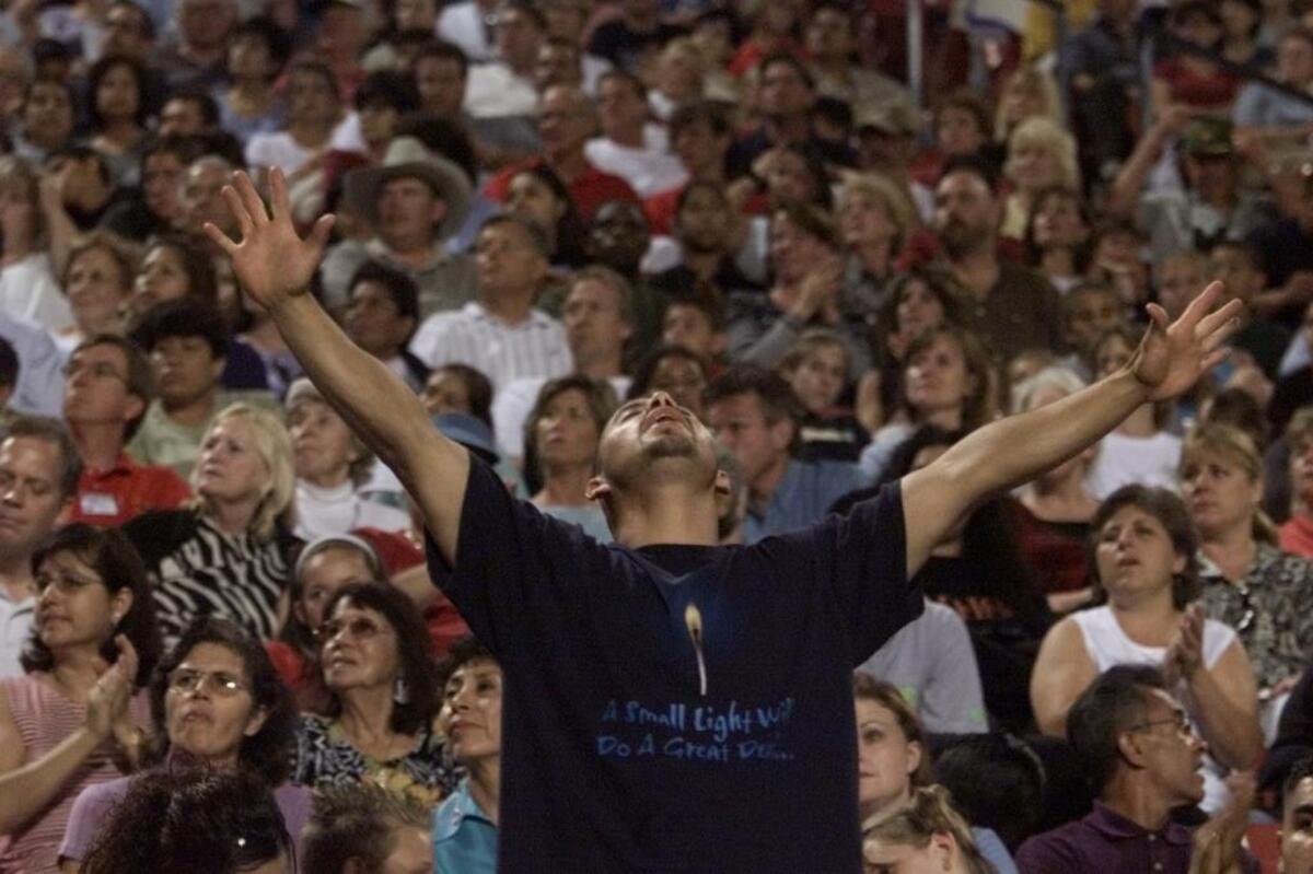 An unidentified man raises his arms in the crowd during the final night of the Billy Graham Crusade at Fresno’s Bulldog Stadium on Oct. 14, 2001. The Rev. Graham died Feb. 21, 2019 at age 99.
