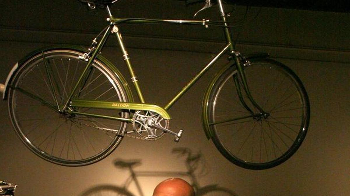 
Edward Lund, in a 2008 event, talks about a table of mementos saved by William Saroyan. Overhead is the author’s old Raleigh bicycle.
