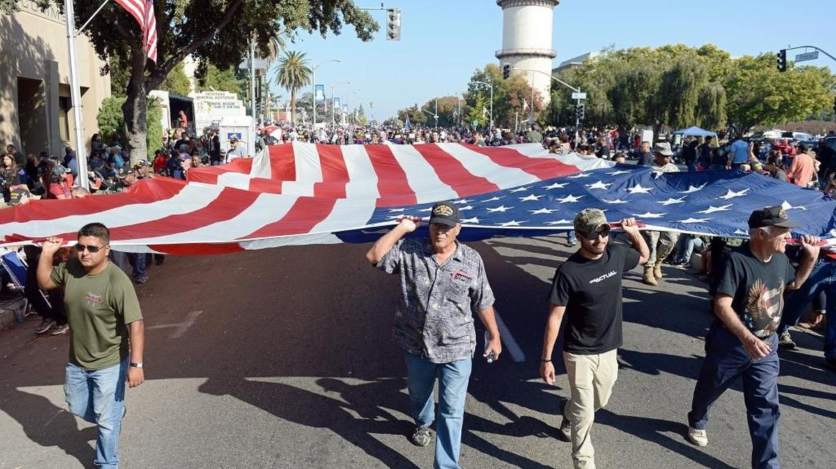 Members from the Fresno Vets Center carry a large American flag down Fresno Street during the 2016 Veterans Day Parade Friday, Nov. 11, 2016.