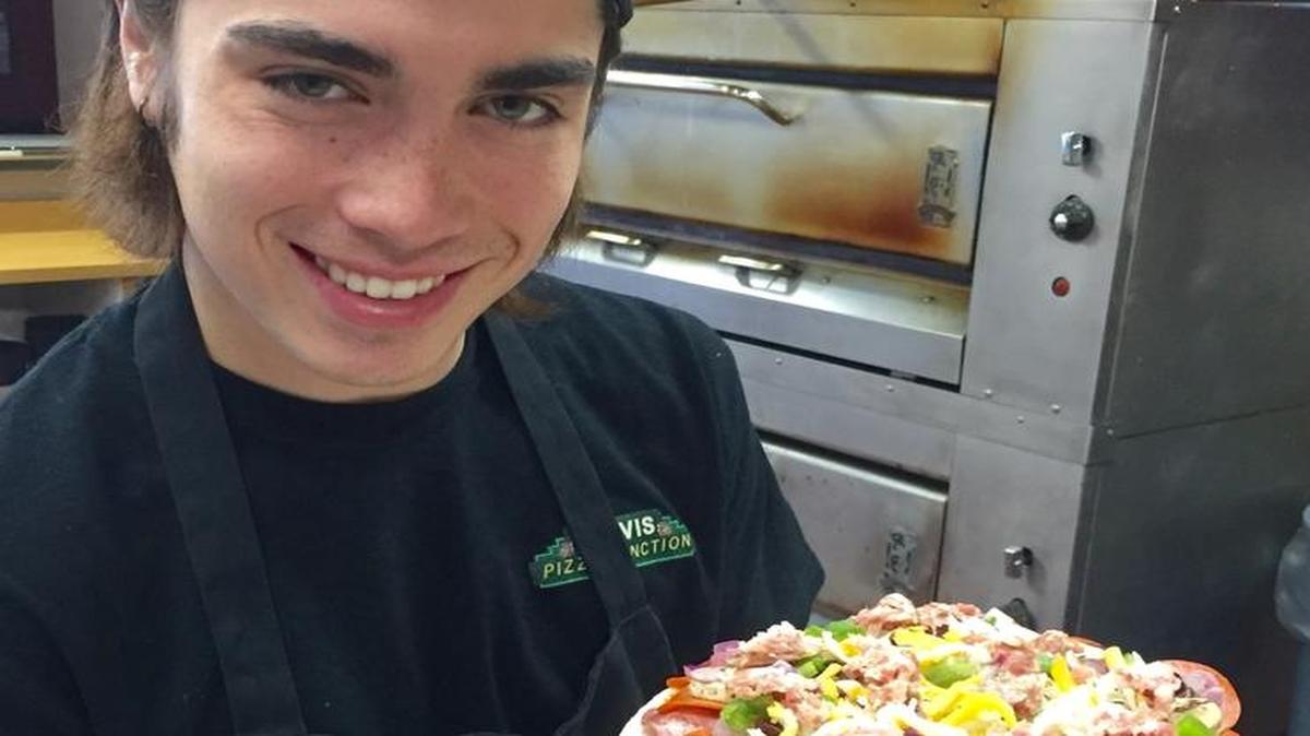 Lucas Baro, an employee at Clovis Pizza Junction, holds a “Clovis Combination” before it goes into the oven.