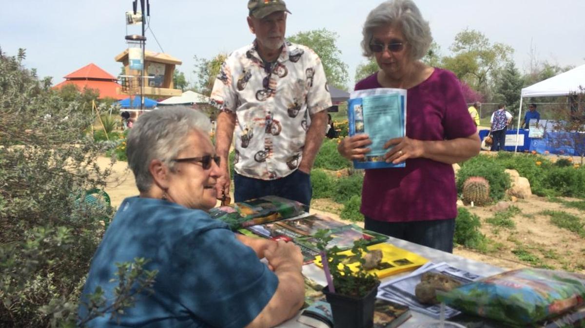 Clovis Botanical Garden volunteer Kathe Weltchek, seated, talks about bird-friendly gardens with Clovis residents George and Sally Smith.