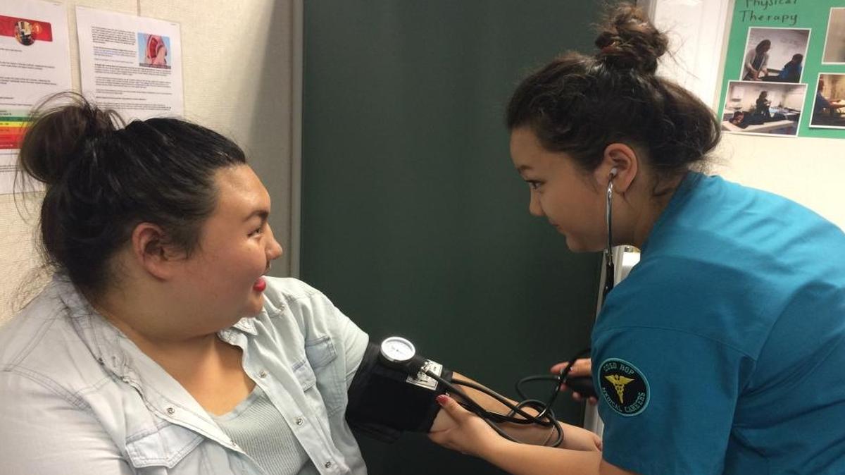 Lily Yang checks the blood pressure of Shannon Moua, left.