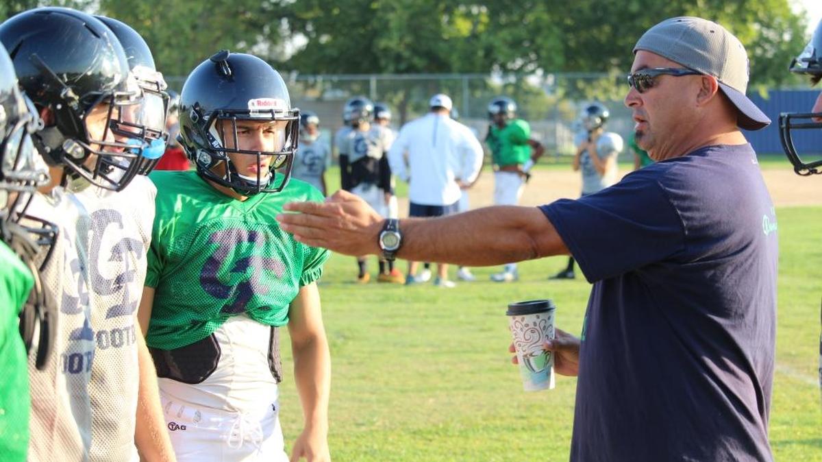 Jim O’Brien, head football coach at Clovis East High School, talks with players at an early-morning practice before the start of the new school year.
