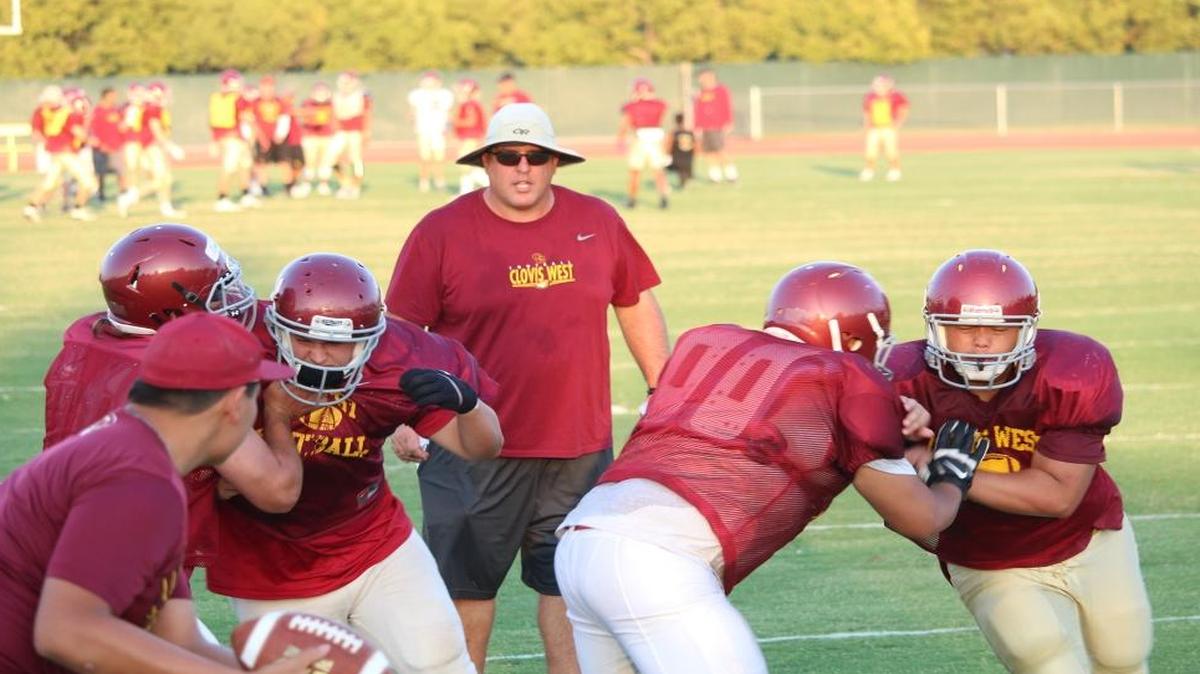 George Petrissans, head football coach at Clovis West High School, leads players through a preseason practice.
