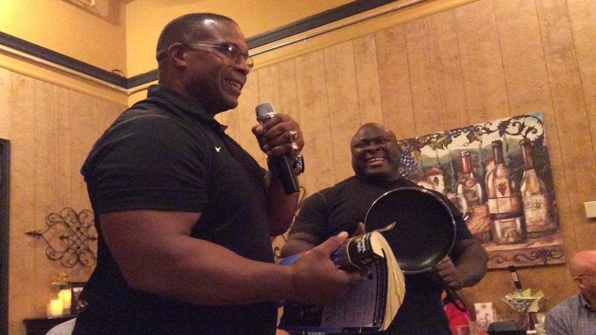 
Former NFL player Keith Davis (left) holds a phonebook and Clarence Lee (right) holds a frying pan — two props that the athletes use in motivational speeches for schoolchildren.
