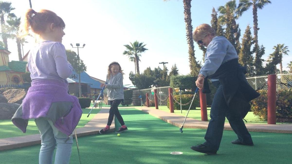 From left, Sydney Hazelton, 8, and her sister Madilyn, 11, watch as their grandmother Lynn Hazelton sinks a putt at Blackbeard’s Family Entertainment Center.