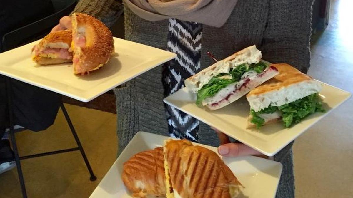 Jaynae Franklin displays some breakfast and lunch menu items: the Sunrise Croissant, the Turkey Focaccia and the Bagelwich.