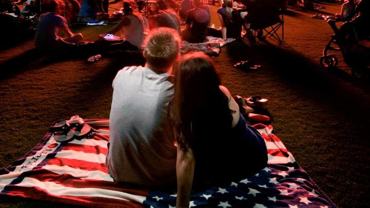 Kyle Epps, left, and his friend Veronica Gregg, right, watch fireworks explode over Veterans Memorial Stadium during the annual Freedom Fest fireworks show held in Clovis on July 4, 2014.