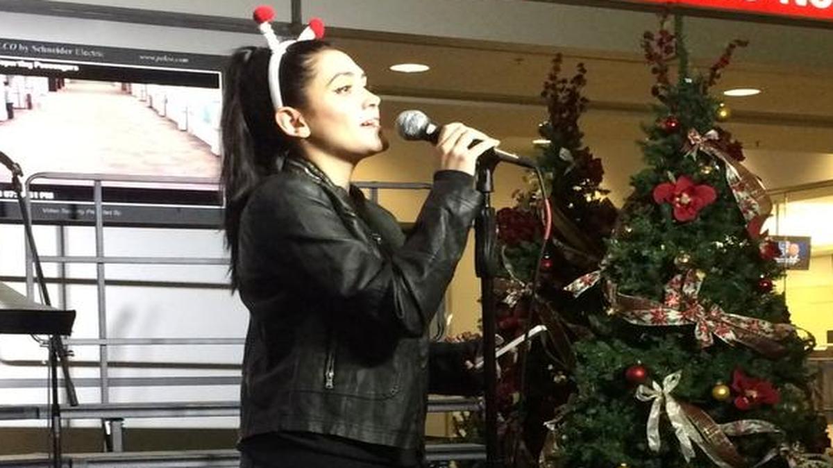Holly Bennett, a senior at Roosevelt School of the Arts, sings a carol during the opening of Santa’s Gingerbread Village at Fresno Yosemite International Airport.