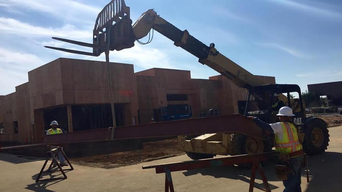 Construction workers from general contractor Zumwalt Construction lift the final beam to be placed on Valley Public Radio’s new Clovis recording studio.