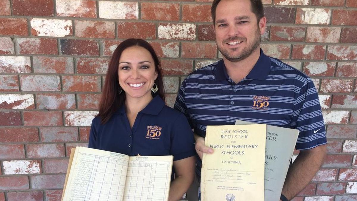 Dry Creek Elementary Parent Association member Lindsay Folmer and Principal Aaron Cook hold decades-old ledgers that were found in a storage area underneath the stage in the school’s multipurpose room. To celebrate the school’s 150th anniversary, school officials encourage former students, staff and administrators to come forward with memorabilia that can be displayed during a carnival set for Sept. 23.