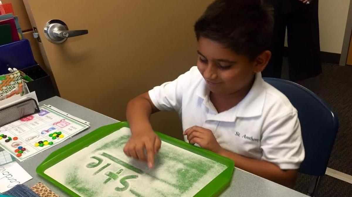 Tristan Cordova writes letters in a sand tray, part of the multisensory Orton Gillingham Method Cullinan Education Center uses in its educational programs.